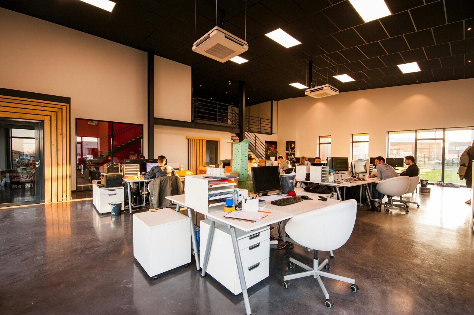 A spacious and modern open-plan office with natural lighting and employees working at desks.